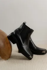 Bota corta tipo chelsea de cuero con textura croco, punta cuadrada con detalle metálico y suela de goma con taco bajo.
