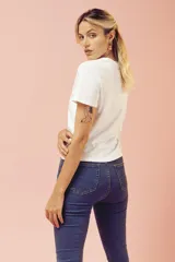 Jeans ajustados de tiro alto en tono azul oscuro, con diseño clásico de cinco bolsillos y terminación desmechada en los tobillos.