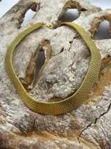 Gargantilla dorada tejida con cierre de gancho.