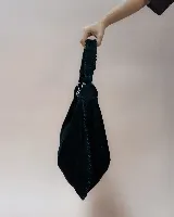 Bolso tipo hobo de gran tamaño, confeccionado en gamuza color marrón oscuro. Presenta un diseño artesanal con costuras visibles y detalles de tientos en el cuerpo, asa integrada con pespuntes a mano y cierre superior.