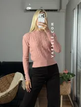 Sweater de tejido de punto con diseño de trenzas verticales, cuello redondo y mangas largas con puños ajustados que presentan detalle de botones metálicos.