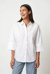 Camisa blanca de manga tres cuartos, cuello camisero y cierre frontal con botones.