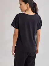 Remera blanca de algodón suave con detalle de bordado en los hombros y cordón ajustable en el ruedo.