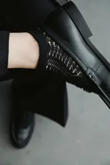 Medias tobilleras de color negro, confeccionadas con un tejido de punto calado estilo crochet y borde elástico superior.