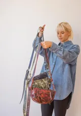 Bandolera de cuero color rojo con detalles en negro, con correa regulable y cierre superior con cremallera.