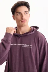 Hoodie y canguro oversize violeta con efecto acid wash, capucha y bolsillo frontal tipo canguro. Presenta un pequeño estampado tipográfico en el pecho con la inscripción 'DAUNTLESS // GOODS & SUCCESS CO'.