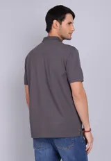 Remera tipo polo de manga corta en color gris oscuro, con cuello clásico y cierre frontal de dos botones. Presenta un pequeño logo bordado en el pecho.