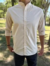 Camisa de manga larga color beige con cuello mao y cierre frontal de botones.