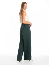 Pantalón palazzo de satén color verde oscuro, con tiro alto, pretina delantera con pasadores, cierre y botón, y pretina trasera elastizada. Cuenta con bolsillos verticales delanteros y corte amplio.