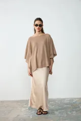 Poncho tejido de punto color tostado, con escote redondo y diseño amplio y asimétrico.