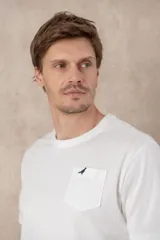 Remera azul marino de algodón con cuello redondo, manga corta, bolsillo en el pecho y logo bordado de un pájaro. Corte clásico.