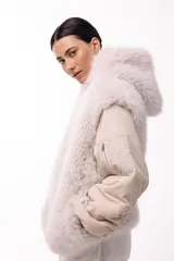 Campera de diseño híbrido con frente y capucha de piel sintética, y mangas acolchadas tipo bomber en color beige. Presenta un bolsillo con cierre en la manga y una silueta amplia y voluminosa.