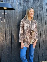 Parka de piel sintética con estampado de serpiente en tonos marrones y beige, con cuello tipo solapa y corte holgado.