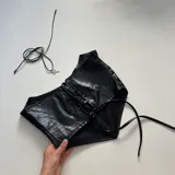 Top negro de cuero sintético con textura de cocodrilo, cierre frontal con cremallera y tirantes finos.