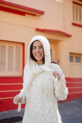 Sweater de lana color blanco con diseño de trenzas y capucha integrada con lazos ajustables.
