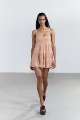 Vestido corto negro de gasa con escote recto y tirantes finos ajustables. El corpiño tiene fruncido elástico y el ruedo es escalonado con volados. Presenta un detalle de encaje a tono en el borde del escote.