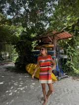 Vestido corto tejido en punto jersey con diseño de rayas horizontales multicolores. Presenta una silueta recta, cuello redondo y terminaciones hechas a mano en crochet.