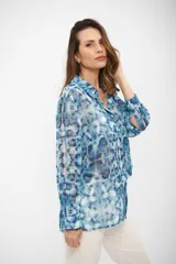 Camisa de manga larga con cuello clásico y cierre frontal de botones, confeccionada en tela liviana con estampado tipo tie-dye en tonos celestes y blancos.