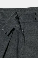 Pantalón wide leg de tiro medio color gris con raya diplomática, confeccionado en hilatura con viscosa. Cuenta con bolsillos laterales ocultos en costura, detalle de pinzas frontales y cierre con cremallera, botón y ganchos metálicos.