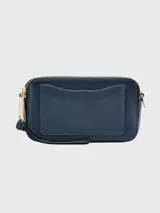 Cartera bandolera Marc Jacobs modelo The Snapshot, color azul con detalles dorados. Presenta doble compartimento con cierre, logo de la marca en el frente y correa de tela con el nombre de la marca.