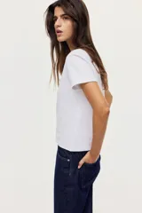 Remera de algodón blanca, de manga corta y cuello redondo acanalado, corte clásico y diseño liso.