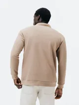 Polo manga larga color beige en tejido piqué, corte regular, con cuello clásico y tapeta de dos botones.