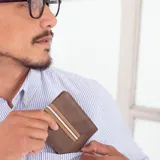 Billetera color beige de símil cuero lisa con galón elastizado marrón con línea blanca. Interior con doble repartición para billetes, visor y tarjeteros.