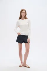 Remera de manga larga al cuerpo confeccionada en viscosa, de color blanco, con cuello a la base y cierre frontal de botones.