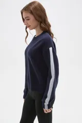 Sweater de tejido jacquard color azul marino, con cuello redondo y diseño holgado. Presenta franjas laterales en color gris claro a lo largo de las mangas largas.