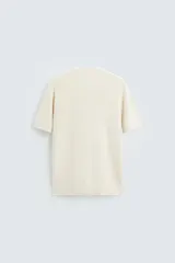 Camiseta negra de punto perlado, corte regular fit, cuello redondo, manga corta y rib en los acabados.