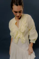 Camisa verde de manga larga, con volados frontales y detalles de puntilla bordada.