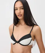 Top de bikini Bossa Nossa con diseño color block en negro y blanco, confeccionado en microfibra con textura plisada. Presenta copa estructurada con aro, breteles finos regulables y un detalle de botón decorativo en el centro.