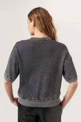 Remera de tejido térmico con lavado burnout, color gris oscuro, de calce boxy y relajado con hombros caídos y mangas al codo. Presenta terminaciones acanaladas en cuello, puños y ruedo.