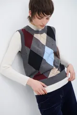 Chaleco de punto con diseño de rombos en tonos beige, marrón y gris. Presenta cuello redondo y corte ajustado a la cintura.