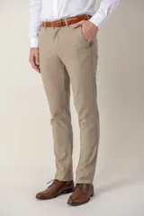 Pantalón de vestir color beige, de corte clásico, con bolsillos laterales y traseros. Se ajusta a la cintura con cinturón de cuero marrón.