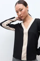 Remera de manga larga con diseño bicolor, presenta un panel central en color beige y laterales en color negro, con escote en V.