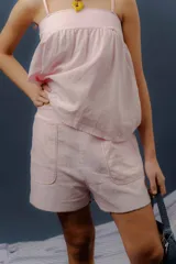 Conjunto de dos piezas confeccionado en lino color rosado, compuesto por una musculosa de corte amplio con breteles de lazo regulables y un short con elástico en la cintura y bolsillos delanteros redondeados.