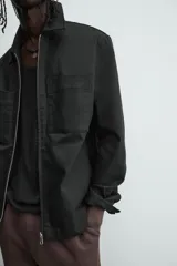 Cazadora azul marino de corte regular fit, confeccionada en tejido técnico repelente al agua. Presenta cuello subido, manga larga, bolsillos de vivo en cadera, bolsillo interior y acabados en rib en puños y bajo. Cierre frontal de cremallera oculta por solapa con botones a presión.