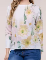 Blusa de silueta holgada y corte recto con caída fluida, escote redondo y mangas largas con puños anchos estructurados, con estampado floral en tonos pasteles sobre fondo blanco.