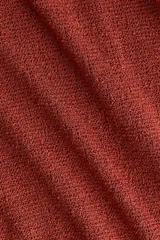 Vestido corto de punto texturizado en color terracota, con escote bote, mangas largas amplias y detalle de tiras anchas para anudar en la cadera.