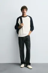 Camiseta de manga larga con estructura waffle, corte regular fit. El cuerpo es de color blanco crudo y las mangas raglán son de color azul marino. Tiene cuello redondo a contraste.