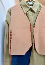 Chaleco artesanal confeccionado en cuero, con diseño de cordones decorativos en el frente y terminaciones rústicas.