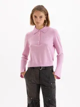 Sweater de punto color rosa, con cuello polo, cierre frontal con botones y mangas largas con puños acampanados.