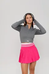 Top deportivo de manga larga en color gris, confeccionado en tejido acanalado. Presenta un diseño ajustado al cuerpo, cuello alto con cierre frontal parcial y aberturas para los pulgares en los puños. Incluye el logo 'bk.' estampado en la parte inferior frontal.