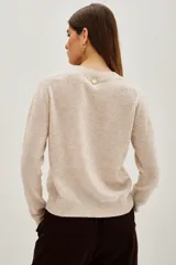 Sweater de punto color beige, con cuello redondo y manga larga. Presenta un corazón rojo bordado en el pecho y la palabra 'l'amour' bordada en el puño de la manga.