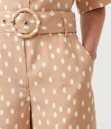 Short color beige con estampado de lunares blancos, tiro medio, trabillas en la cintura y cinturón forrado con hebilla.