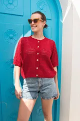 Saco de tejido calado color rojo, con mangas al codo, cuello redondo y cierre frontal con botones de coco. Presenta un diseño versátil y ligero, ideal para media estación.