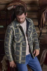 Sobrecamisa leñadora de polar a cuadros en tonos verde militar, beige y azul claro. Cuenta con dos bolsillos frontales con solapa, dos bolsillos laterales y cierre con botones a presión. Interior de micropolar.