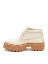 Bota tipo chukka de Caterpillar, color beige, con plataforma alta y suela dentada de goma color caramelo. Presenta cordones al tono, ojales metálicos dorados y logo de la marca grabado en el lateral y la lengüeta.