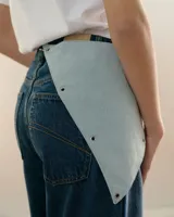 Bandana triangular de tela con estampado a cuadros en tonos verde y azul marino. Presenta ojales metálicos distribuidos en los bordes para la personalización con accesorios y un aro metálico en la punta inferior.